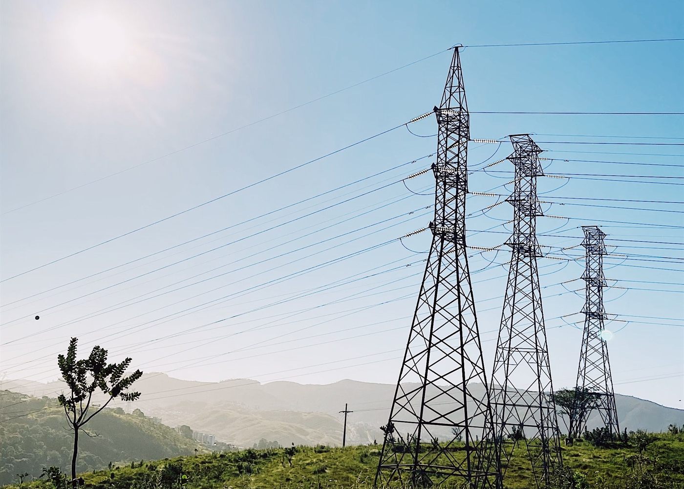 Linhas de transmissão de energia cruzando área rural ao amanhecer