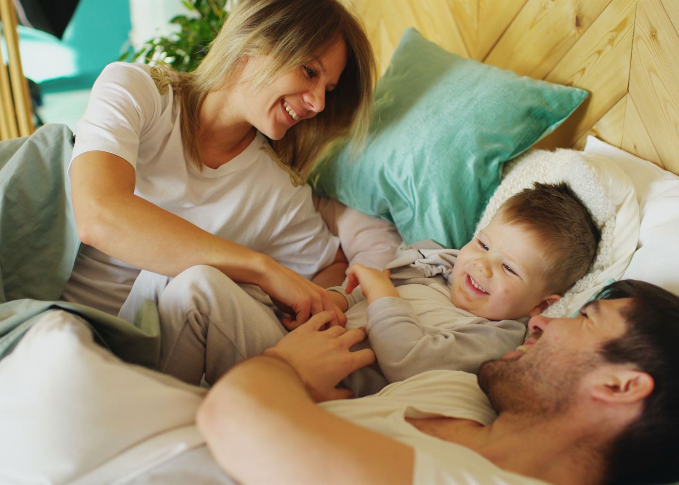 Pai, mãe e filho pequeno brincando juntos na cama pela manhã